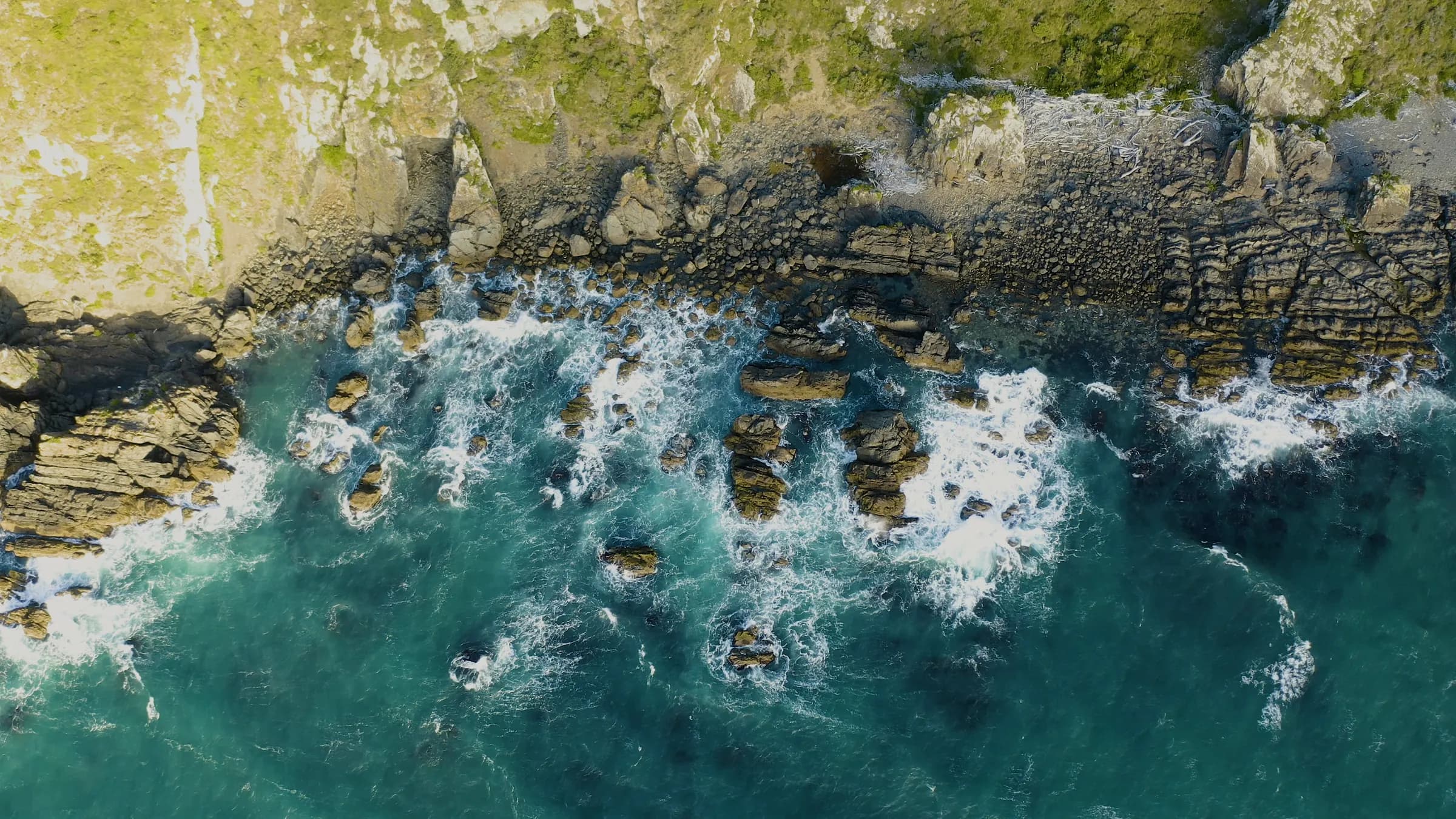 Aerial view of waves breaking against a rugged New Zealand coastline